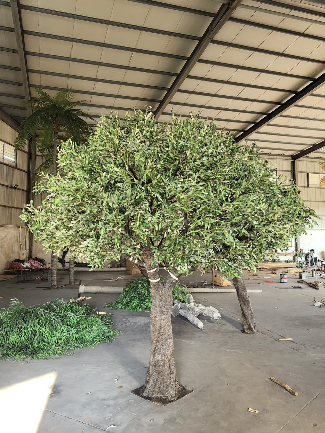 Twin-trunk artificial olive tree with detailed bark finish in the workshop