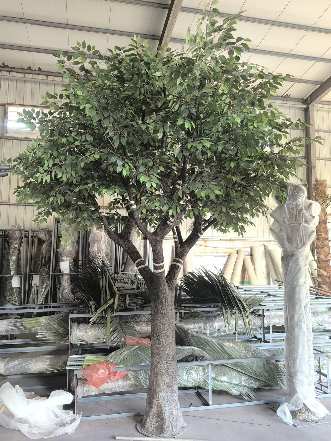 Large artificial ficus tree with multiple trunks under construction in the workshop