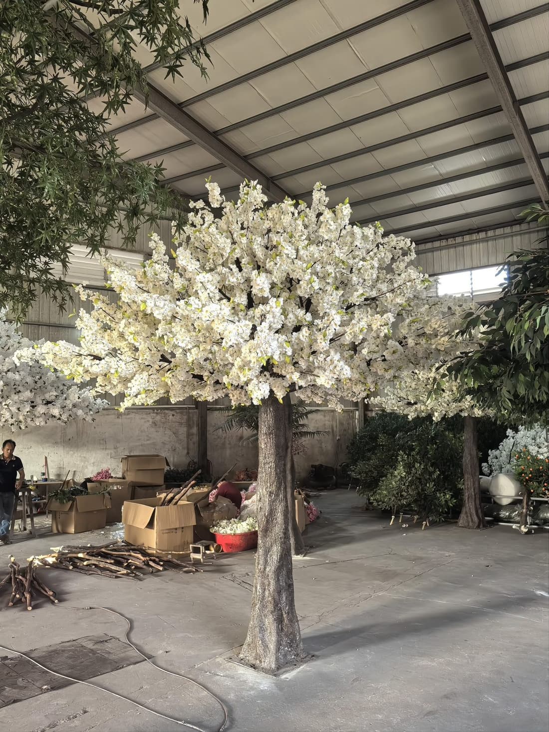 White-blossom artificial cherry blossom tree on the workshop floor with the canopy dressed by hand