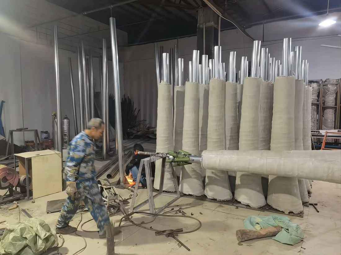 Fibreglass trunk wrapping line — trunks curing upright, steel cores in place before finishing