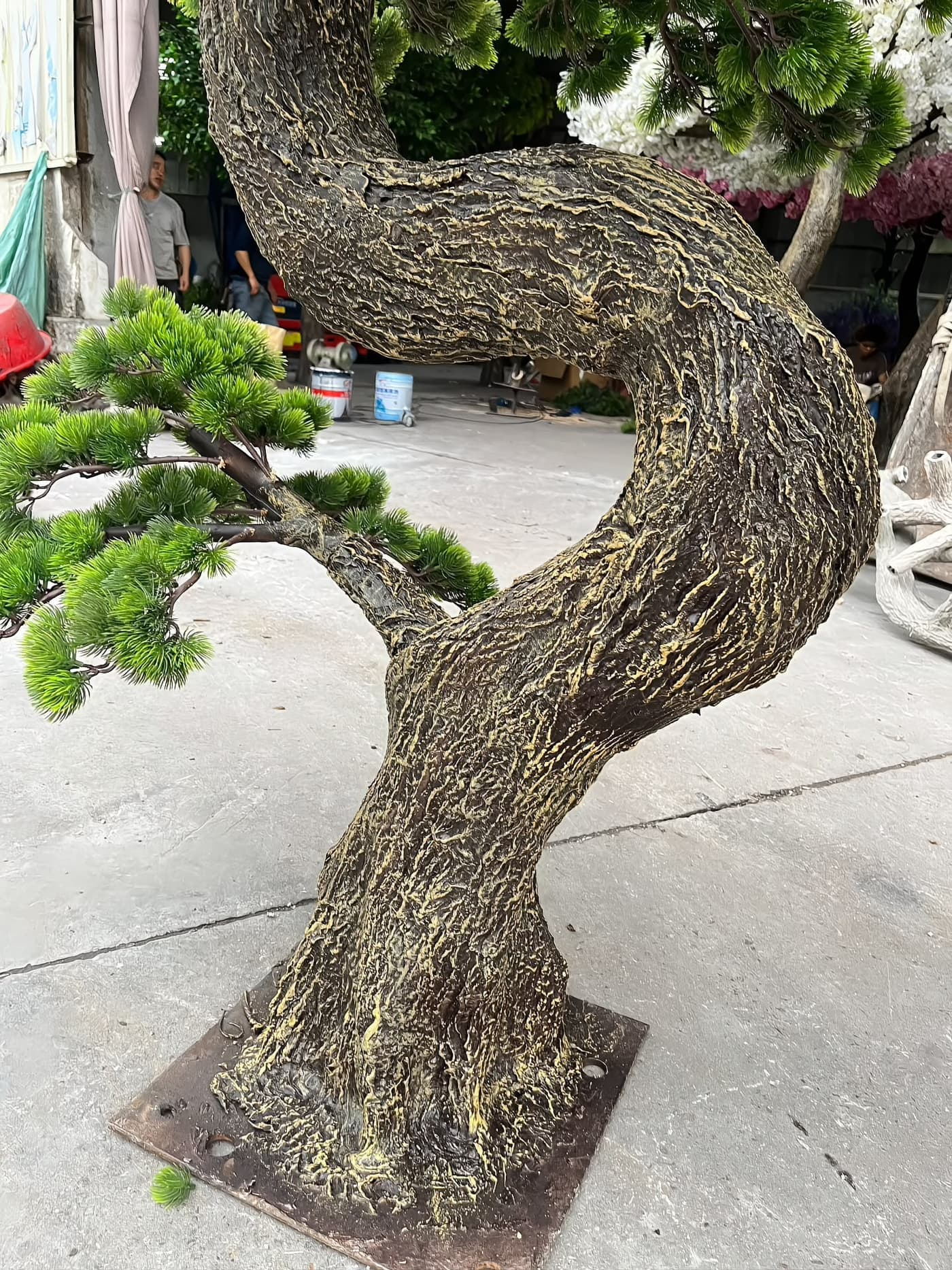 Hand-carved and painted bark texture on a sculpted trunk standing on its bolted base plate