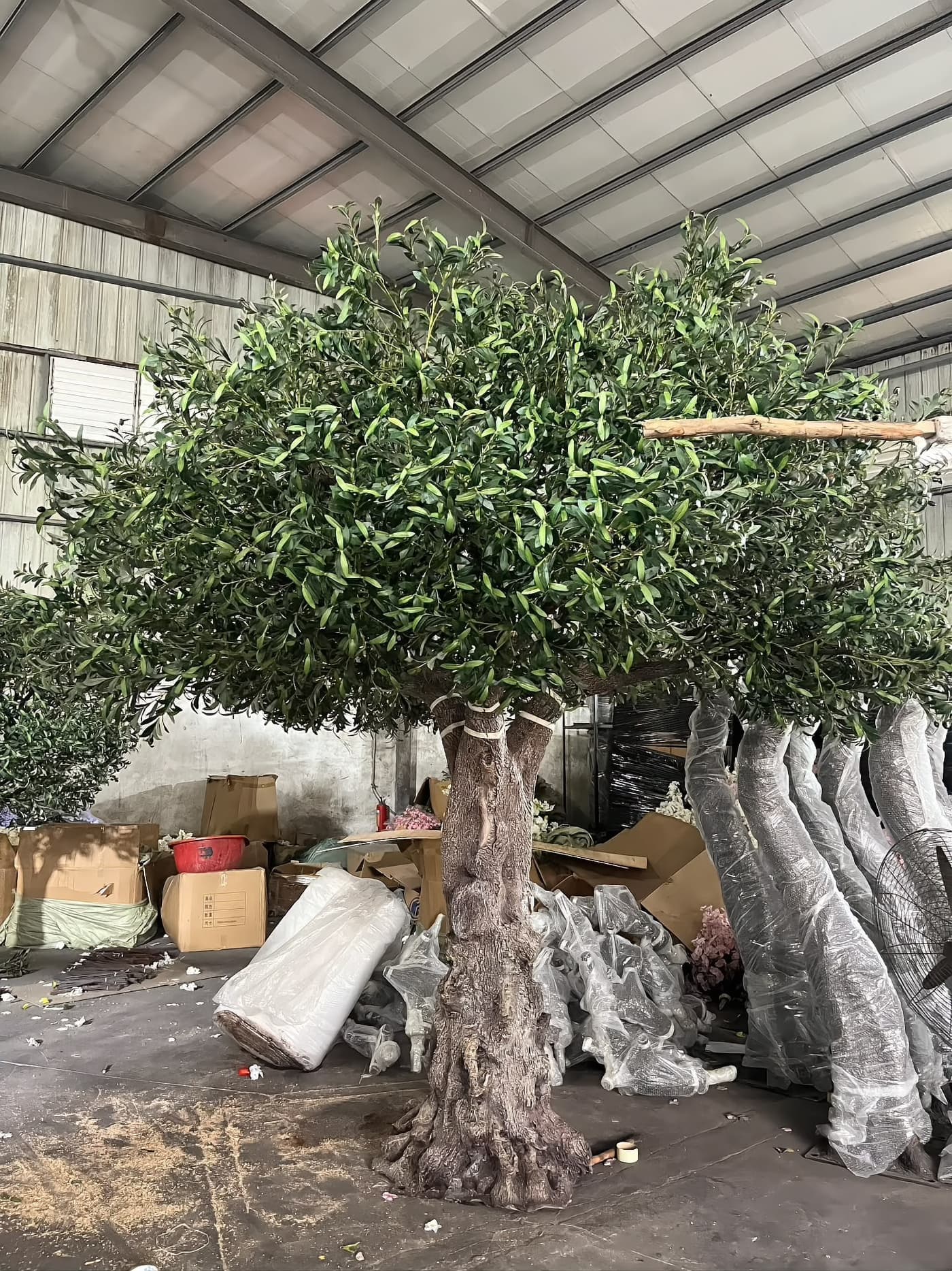 Root flare and lower trunk detail of an artificial olive tree, the area checked for base fixings and trunk joints