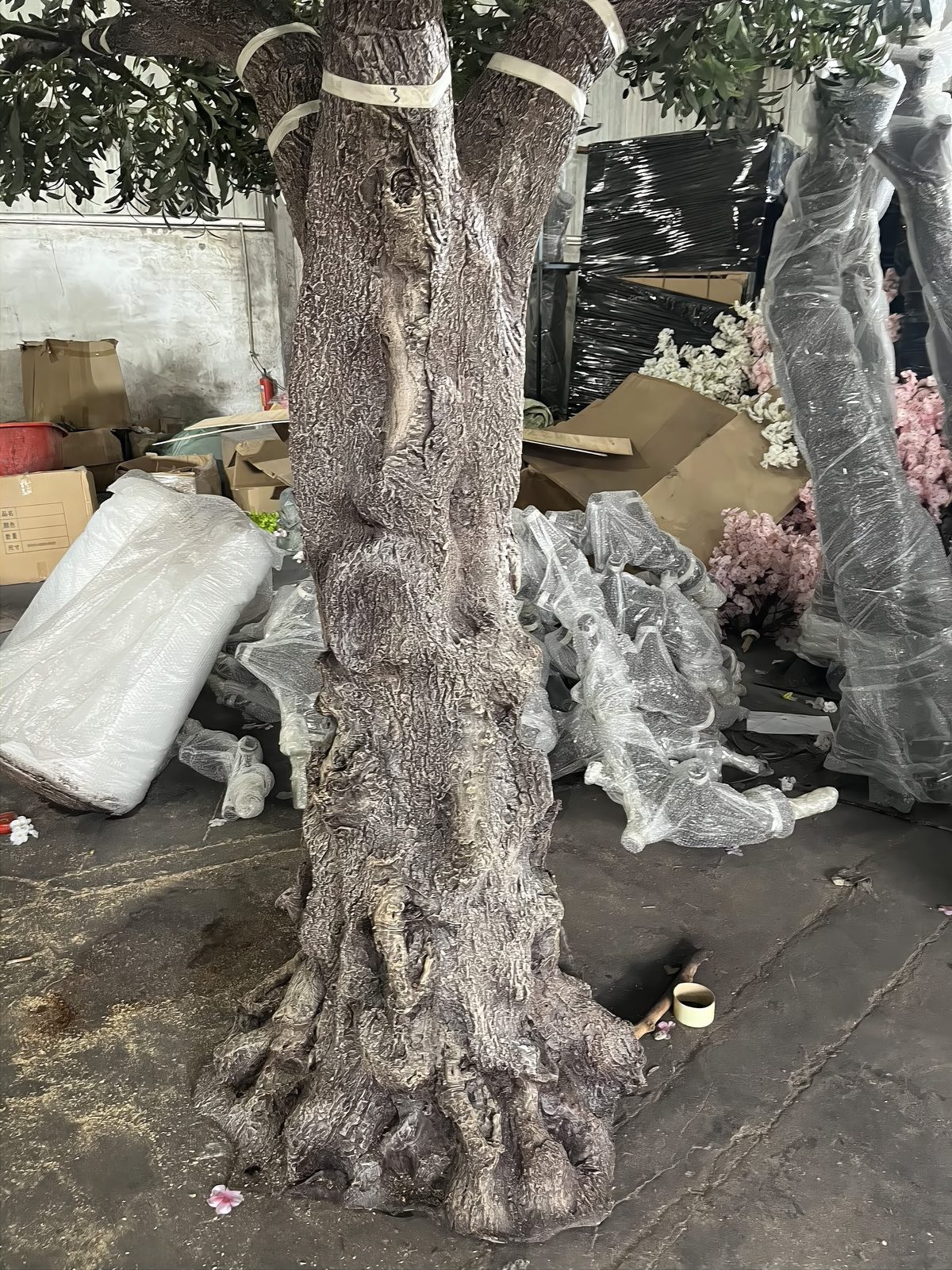 Close-up of hand-applied bark detail on an artificial olive trunk in the workshop