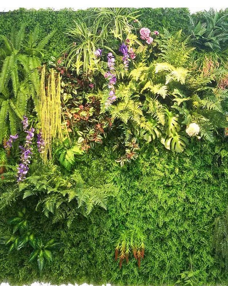 Dense mixed-foliage artificial hedge panels installed edge to edge on a project wall