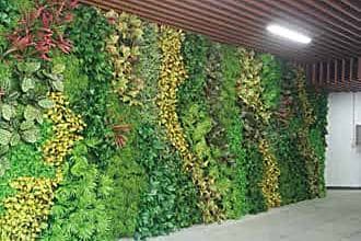 Mixed artificial foliage wall with grasses and colour accents lining a shopping mall walkway